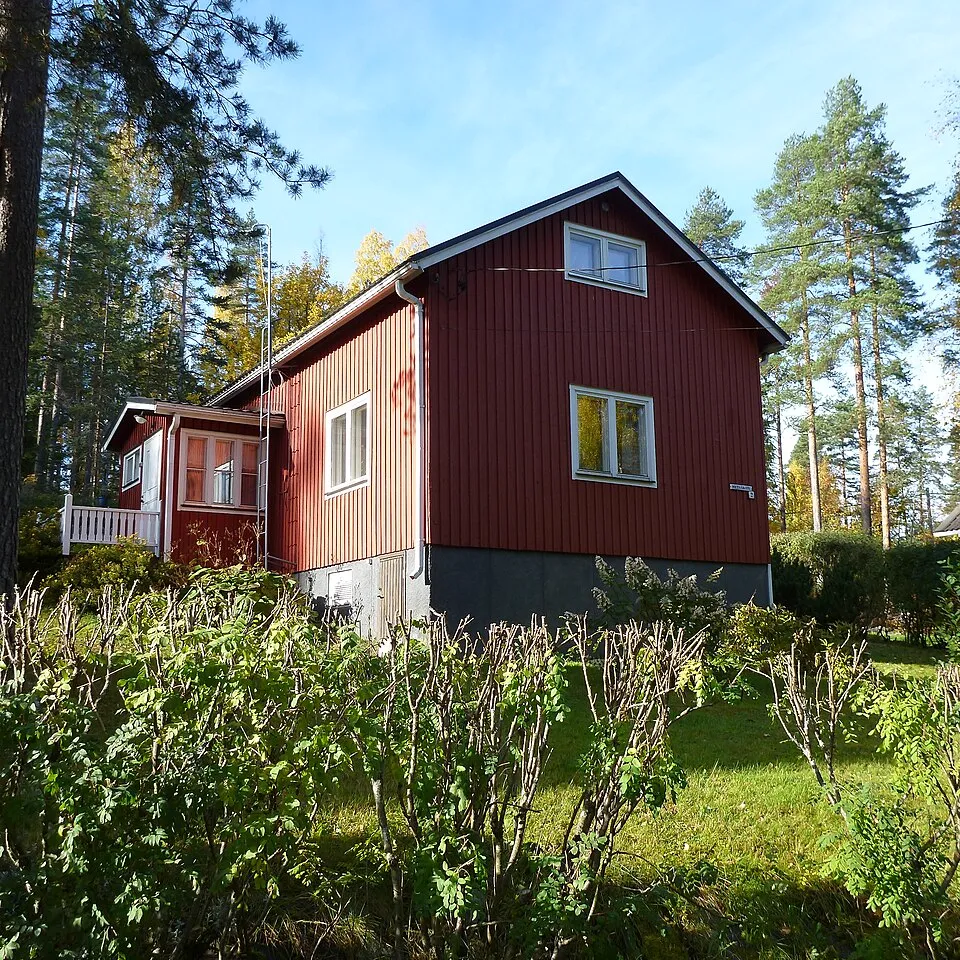 Punamultainen puutalo tummalla peltikatolla